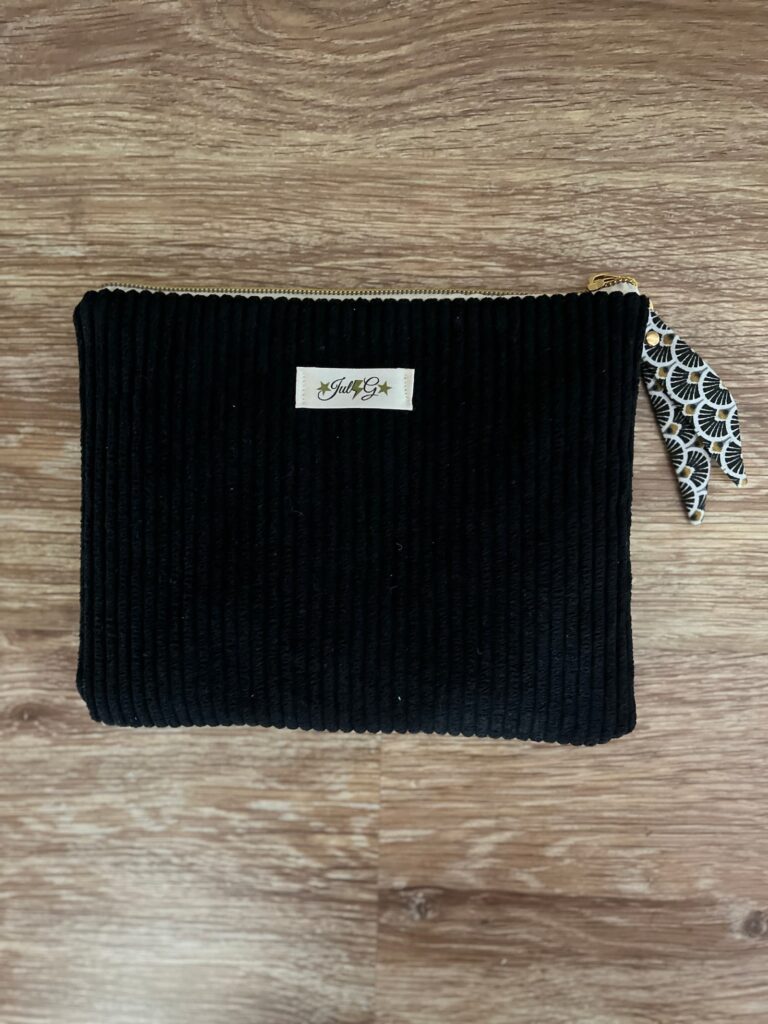 Dos de la pochette matelassée en velours côtelé noir avec étiquette artisanale et ruban japonais